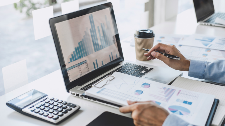 Small business corporation financial management - employee managing finances in table with laptop, calculator, and graphs.