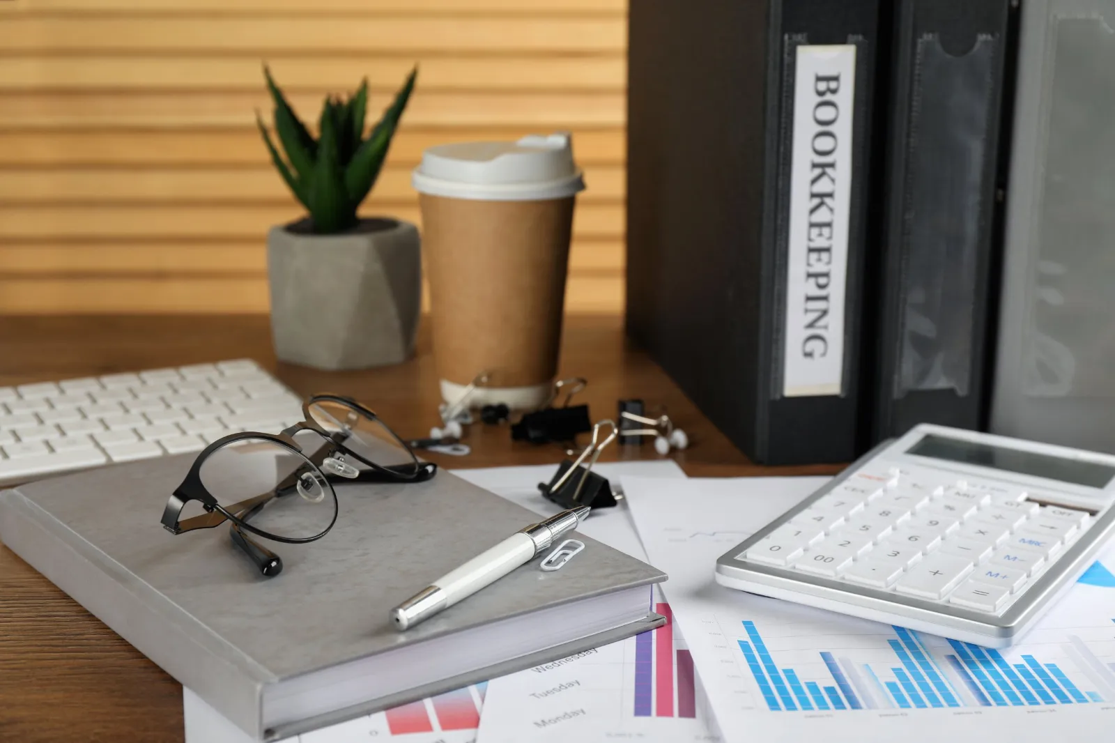 Bookkeeping binders, calculator and financial charts on a desk