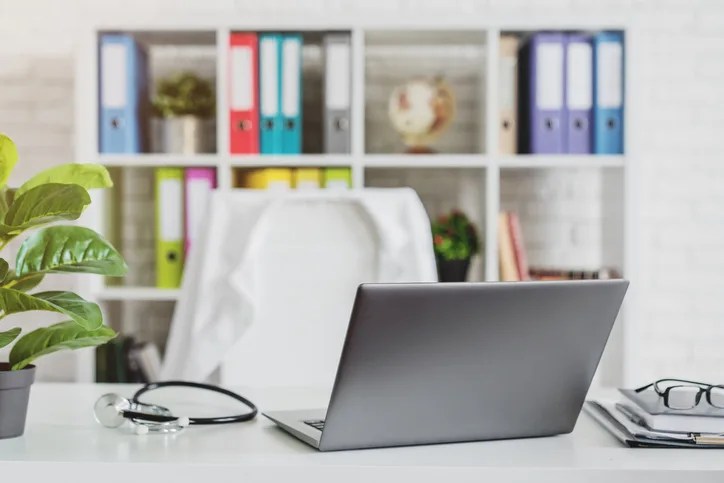 Medical office with a laptop, stethoscope and white coat