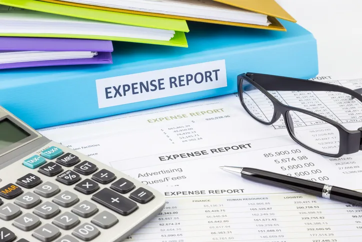 Expense reports with folders, glasses and a calculator